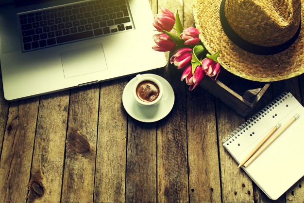 تصویر استوک لپ تاپ با فنجان قهوه و گل روی چوب -  